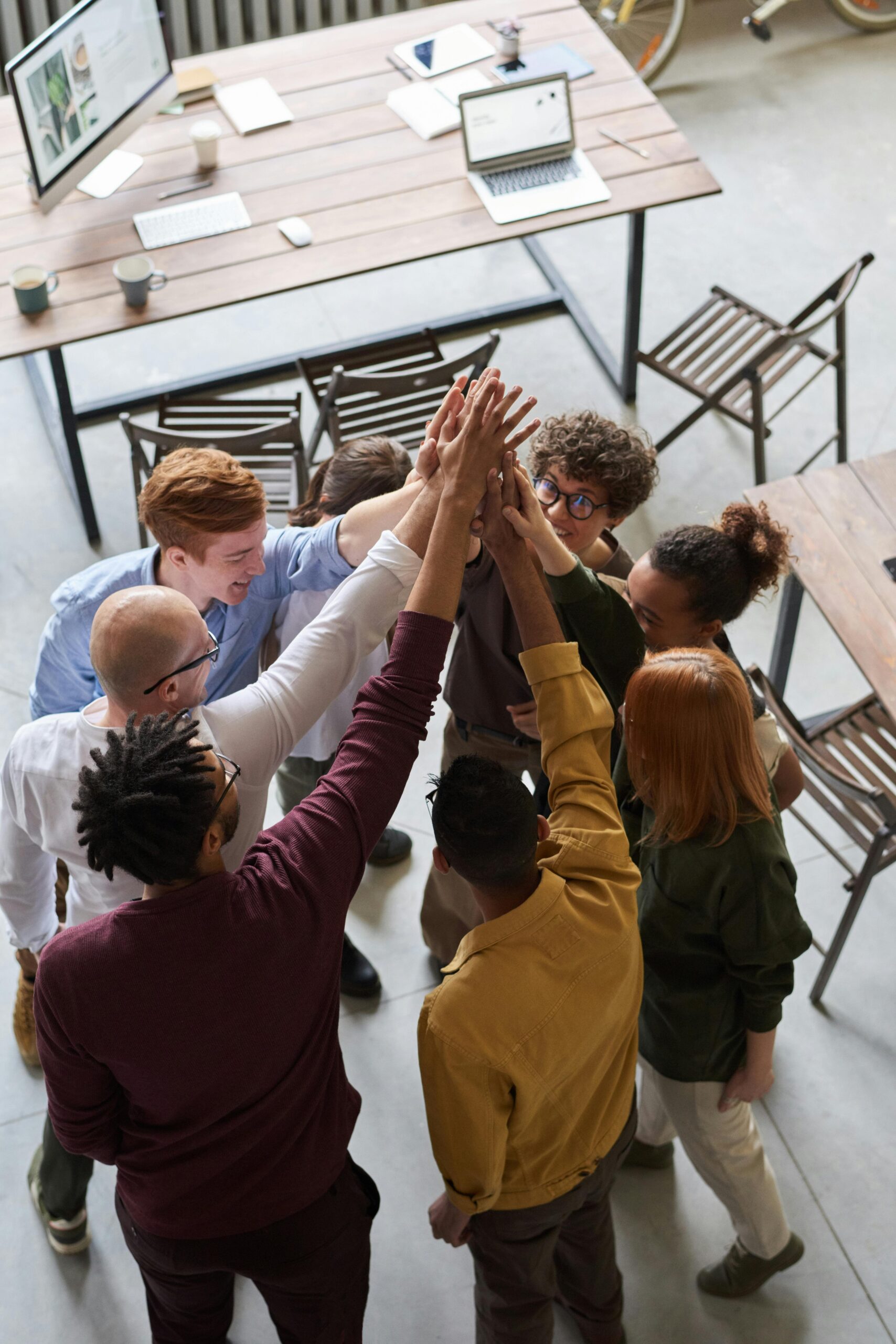 about-us A diverse group of professionals high-fiving in a modern office, showcasing teamwork and collaboration.